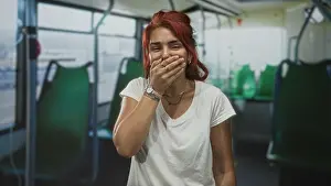 Latina Prints: Woman with hand over mouth laughing on bus interior while seated