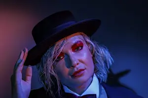 Looking At The Camera Prints: Woman with hat and red eye shadow poses expressively under colourful lighting, photo shoot