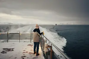 Brim Prints: Woman holding snowy boat railing on Norwegian fjord near Tromso