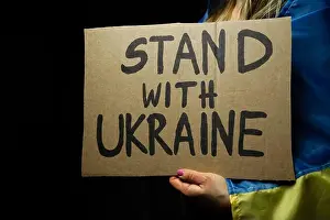 Manifestation Prints: Woman holding Ukrainian flag and Stand With Ukraine placard sign in protest manifestation against Russia invasion