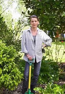 Contemplating Prints: Woman leaning on spade in middle of her garden surrounded by bushes