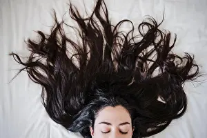 Eyes Closed Prints: Woman with long hair lying on bed at home