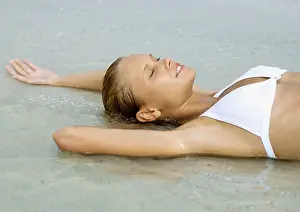 Eyes Closed Prints: Woman lying in shallow water on beach, eyes closed