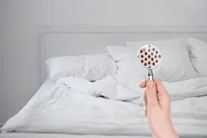 Bedsheet Prints: Woman with magnifying glass detecting bed bugs in bedroom