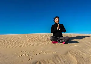 Eyes Closed Prints: Woman meditating on sand during sunny day