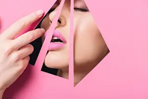 Triangles Prints: Woman with open mouth, closed eyes and pink lips across holes touching paper with hand on black background