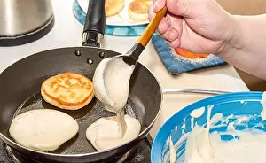 Burnt Prints: The woman is pouring the dough into a hot frying pan. Cooking pancakes at home. Close up