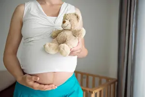 Taking Prints: Woman pregnant close-up holding teddy bear stomach