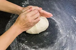 Rolling Prints: Woman preparing pizza dough on black granite table
