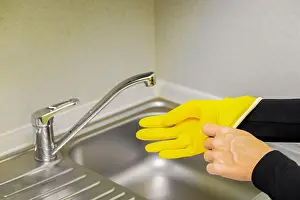 Sink Prints: woman puts on rubber gloves while cleaning the kitchen