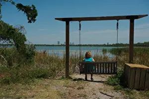 Reeds Prints: Woman Relaxing on a Empty Lakeside Swing Amid Scenic Natural Surroundings