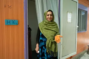 Refugee Camp Prints: A woman is seen holding her hand died with Henna outside her home in Eleonis camp in Athens