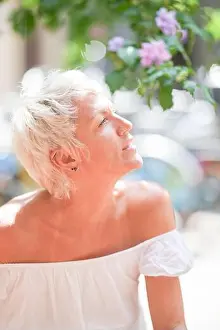 Ukrainian Prints: A woman with short blonde hair and a nose ring is sitting on the ground and looking up at the sky