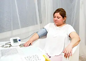Bracelet Prints: Woman sitting in a chair with her arm resting on a table while taking her blood pressure with an electronic machine