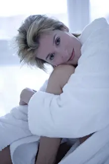 Awake Prints: A woman sitting on the edge of a bed hugging her knees, close up