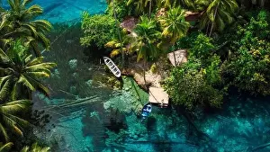 Woman sitting on pier in transparent lake with transparent blue water in Indonesia. Aerial view