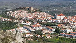 Woman sitting on a rock viewing Castelo de Vide in Alentejo, Portugal from Serra de Sao Mamede mountains