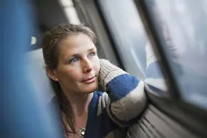 Dreaming Prints: A woman sitting at a window seat in a train carriage resting her head on her hand Looking into the distance