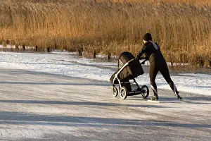 Stock Photos Prints: A woman is skating with a childrens buggy on the famous dutch Bonkevaart Friese Elfstedentocht