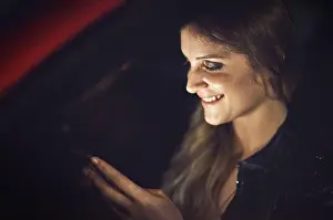 Texting Prints: Woman, smile and smartphone in car at night with transport for travel with technology for communication