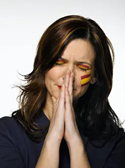 Eyes Closed Prints: Woman with Spanish flag painted on face, praying