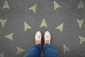 Confusion Prints: Woman standing near yellow arrows on asphalt road