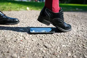 Careless Prints: Woman step on the phone. Broken and damaged smartphone with cracks on glass screen laying on ground