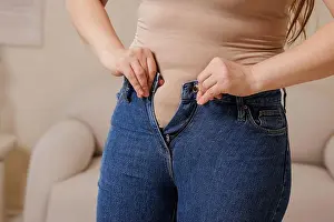 Weight Loss Prints: Woman struggling to fasten jeans highlights challenges of excess weight