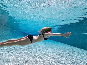 Swimmer Prints: A woman swimming underwater in a pool, wearing a black bikini