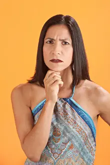 Worry Prints: Woman thinks with hand on chin over an orange background
