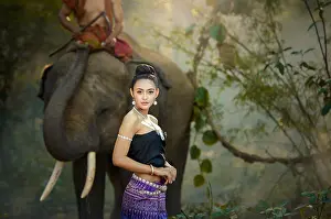 Beautiful Woman Prints: Woman in traditional Thai clothing with a mahout riding an elephant, Thailand