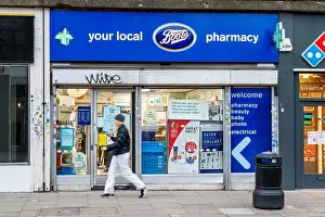 Camden Prints: A woman walks past a Boots pharmacy in Kentish Town, London, UK