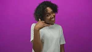 Invite Prints: Woman wearing white t shirt with curly hair and nose ring making call gesture in studio; warmth and connection
