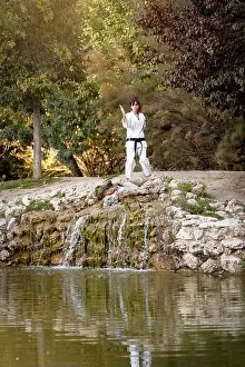 Kimono Prints: Woman in white kimono with black belt looking at camera while training karate outdoors in the nature