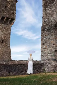 Parasol Prints: a woman in a white period dress is standing at a stone wall with a parasol