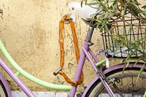 Tied Prints: A woman's bicycle is tied to an iron pole