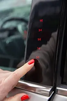 A woman's hand enters the secret code for opening the car door on the touch panel