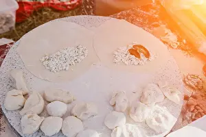 Rolling Prints: woman's hands making qutab or chebureki with a rolling pin