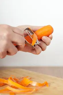 Cutter Prints: woman's hands removing the outer layer of a carrot with a julienne cutter