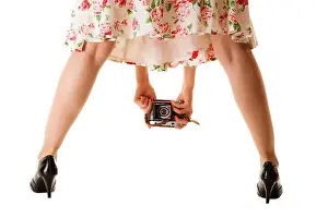 Woman's legs and hand, unusual back view of girl taking picture using vintage camera isolated on white background