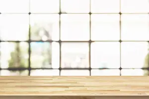 Defocused Prints: Wood table top with blur bright square transparent window of cafe in background - can be used for display your products