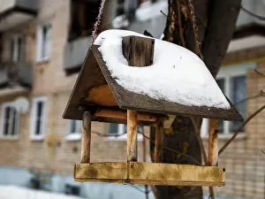 Wooden House Prints: Wooden bird feeder in form of house with pipe on winter day. Selective focus