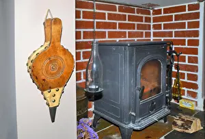 Fireplace Prints: wooden fire bellows hanging close to an indoor wood burning stove situated in converted fireplace