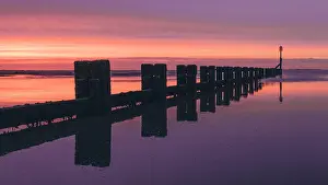 Early Morning Prints: Wooden groin on Cleethorpes Beach, Lincolnshire at sunrise with dramatic purple light