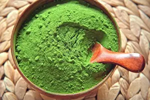 Dietary Prints: Wooden spoon with powdered matcha tea in a bowl spinning on natural background