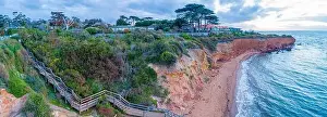 Coastlline Prints: Wooden stairs descending to secluded ocean beach below cliff at sunset