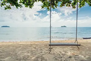 Wooden swing chair hanging on tree near beach at island in Phuket, Thailand. Summer Vacation Travel and Holiday concept