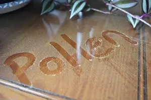 Allergies Prints: The word 'pollen' is written in pollen that has collected on a glass table top near an open window