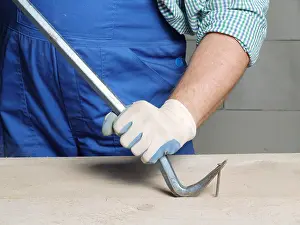 Pulling Prints: Worker pulling a nail from a plank using wrecking bar