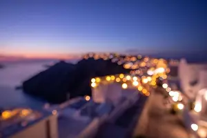 World environment day concept: Bokeh light and blur of sunset twilight town on Santorini, Greece. Sea view and island landscape, abstract cityscape
